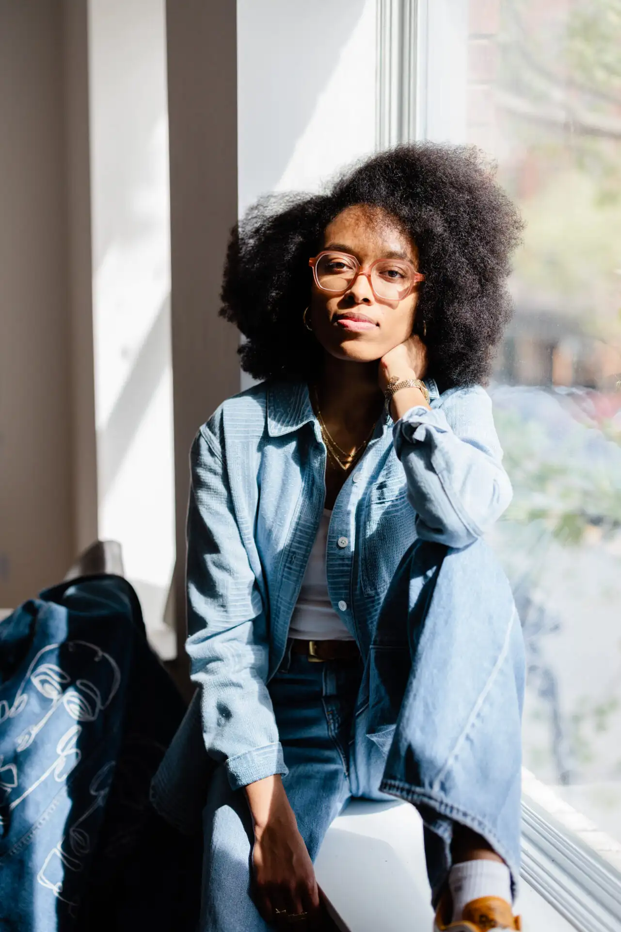 Vanessa Villarreal sitting next to an up-cycled denim jacket she customized for her brand, Lion’s Den Creative.