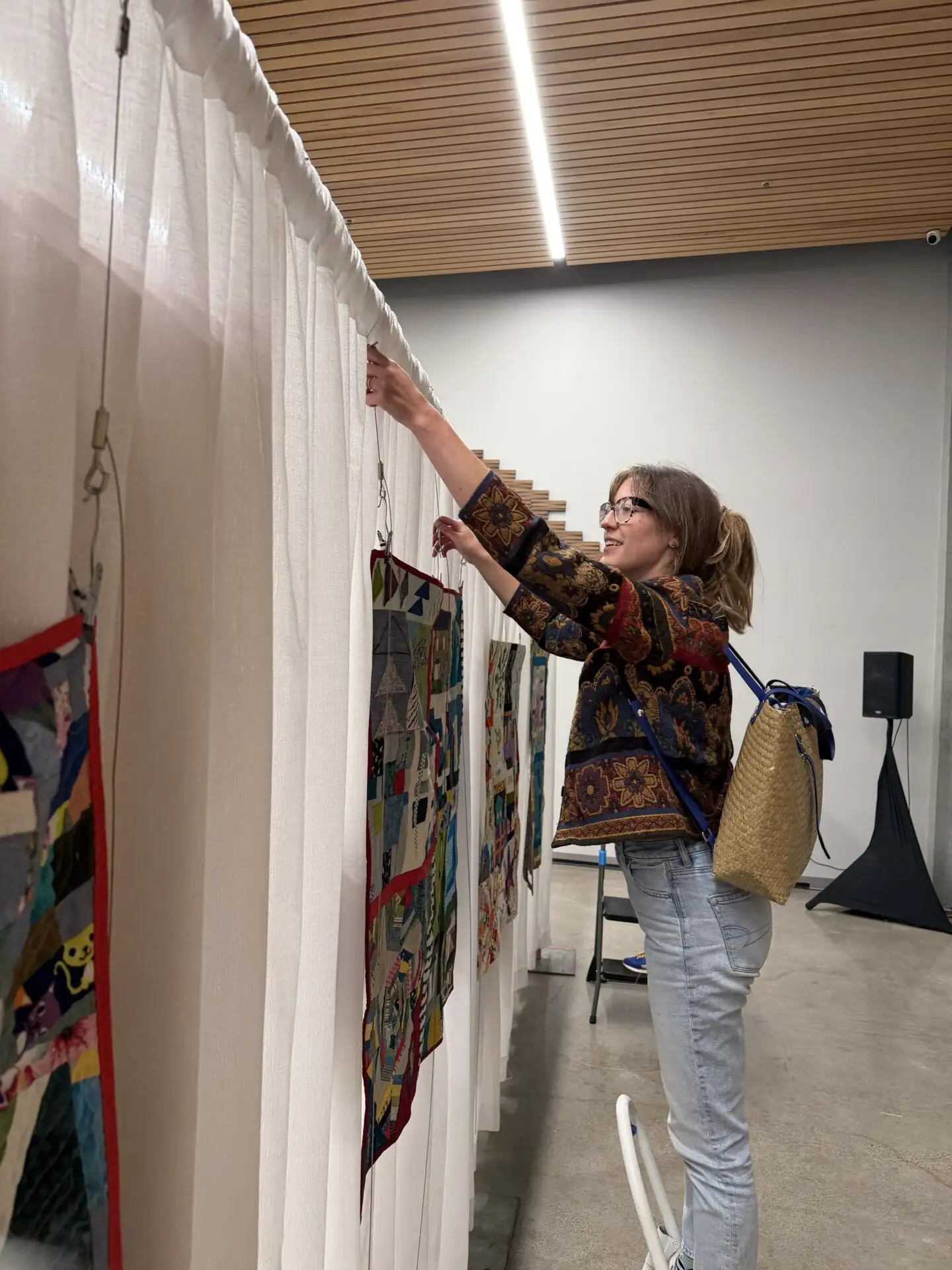 Emily Pillard helps to hang quilts.